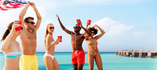 summer, holidays and people concept - group of happy friends with flag and non alcoholic drinks...