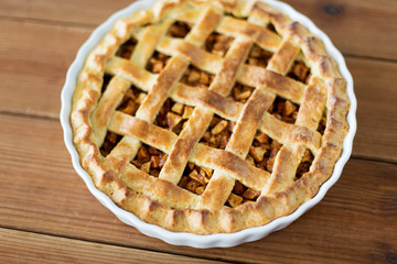 food, culinary and baking concept - close up of apple pie in mold on wooden table