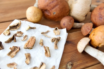 culinary, food and cooking concept - dried mushrooms on baking paper on wooden background