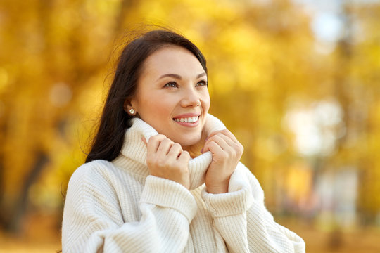 season and people concept - portrait of happy young woman smiling in autumn park