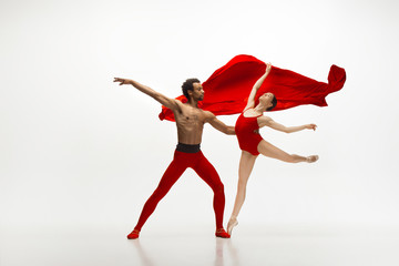 Graceful classic ballet dancers dancing isolated on white studio background. Couple in bright red...