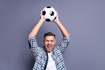 Portrait of his he nice attractive cheerful cheery glad bearded guy wearing checked shirt holding in hands raising up soccer ball isolated over blue violet purple pastel background