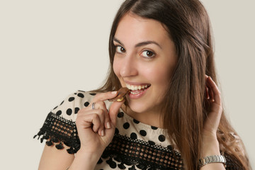 Young attractive woman eating a piece of chocolate, studio shot