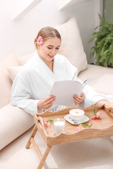 Beautiful young woman reading magazine in spa salon