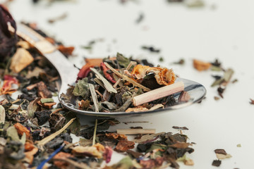 Dried tea heaped teaspoonful on white background, closeup