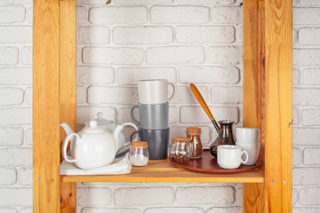 Kitchen utensils and dishware on wooden shelf