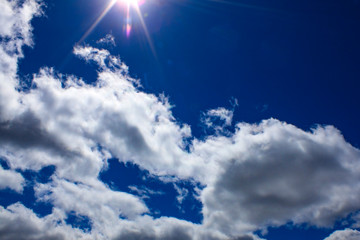 white clouds and sun rays in the blue sky