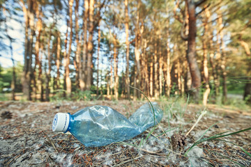 Young  girl picking up the garbage and putting it in a garbage bag on a natural background.