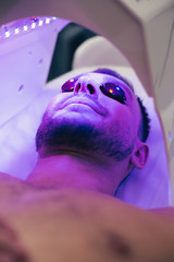 Calm man resting in solarium in beauty salon