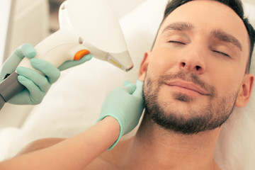 Peaceful man smiling and relaxing at the laser procedure