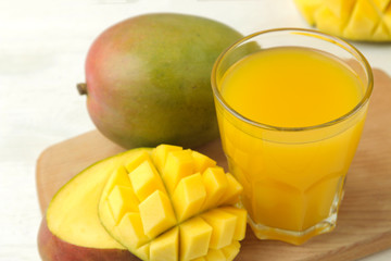 Ripe fresh mango fruit and mango juice in a glass on a light background. tropical fruit