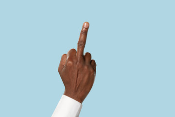 Male hand in white shirt demonstrating a gesture of fuck isolated on blue studio background. Concept of business, office, work. Negative space to insert your text or image.