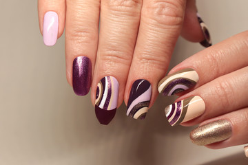Manicure on a different form of nails with a brilliant varnish on a background of a beige and...