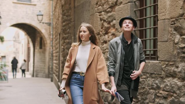 Beautiful and style friends walking with map and camera through tight street.