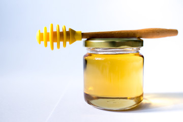 honey in glass jar with wooden dipper