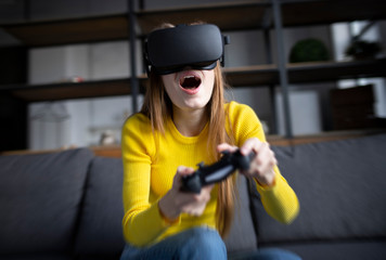 Cute girl plays the game on the console. Happy young woman using a virtual reality headset