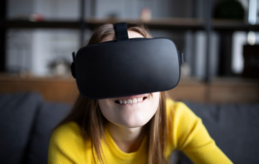 Cute girl plays the game on the console. Happy young woman using a virtual reality headset