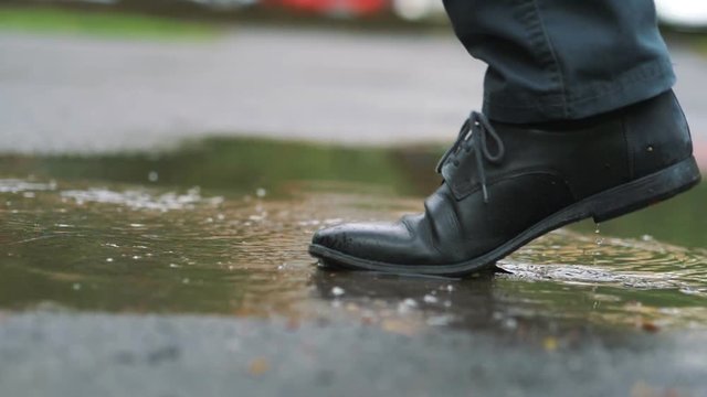 Man in black shoes stepping into the puddle in slow motion 180fps
