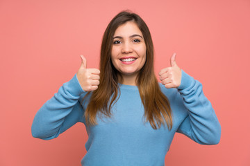 Young girl with blue sweater giving a thumbs up gesture
