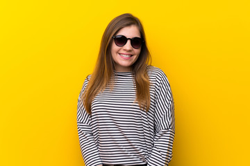 Fototapeta premium Young girl over yellow wall with glasses and happy
