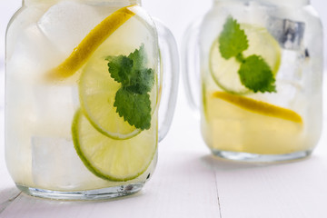 Cold Lemonade with Ice. Lemon and Mint Leaves in Mason Jar on Dark Wooden Background.