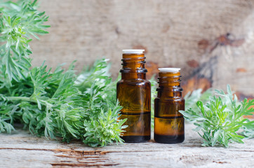 Two small bottles with essential wormwood oil (extract, tincture, infusion). Old wooden background....