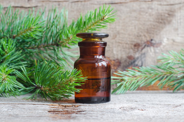 Pharmacy bottle with essential pine oil (extract, tincture, infusion). Old wooden background. Aromatherapy, spa and herbal medicine concept. Copy space.