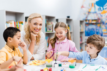 selective focus of happy woman looking at camera near cute kids