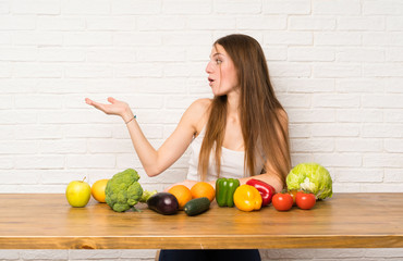 Young woman with many vegetables holding copyspace imaginary on the palm