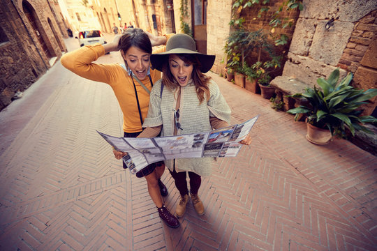 friends with map in the city. Two girls travel together.