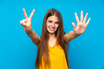 Young woman with long hair over isolated blue wall counting seven with fingers