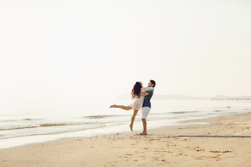 Fototapeta na wymiar Happy couple in love has fun on the beach. They jump, laugh and enjoy the sea