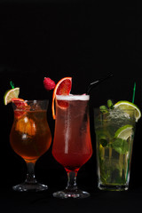 three cocktails on a black background, bright beach, non-alcoholic mojito and May Tai
