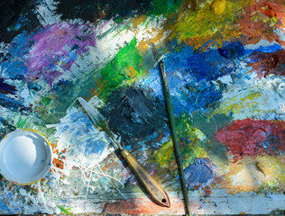 Artistic paintbrushes and palette knifes on old  palette