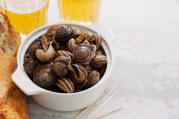 boiled snails with herbs in white bowl on ceramic background