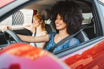 Two young women friends driving in the city - Millennials use the car to get around