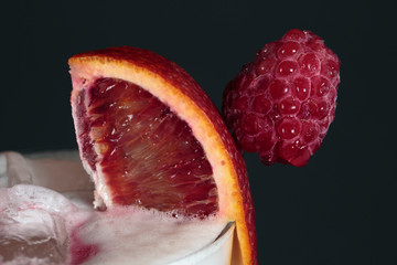 Sacilian orange and ripe raspberry as an addition to the cocktail, shot with empty space and black background