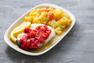 boiled fish with red pepper, vegetables and olive oil on white dish