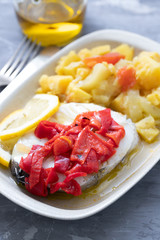 boiled fish with red pepper, vegetables and olive oil on white dish