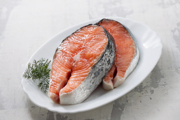 raw salmon with dill on white dish on ceramic background