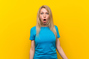 Young blonde woman over isolated yellow background with surprise facial expression