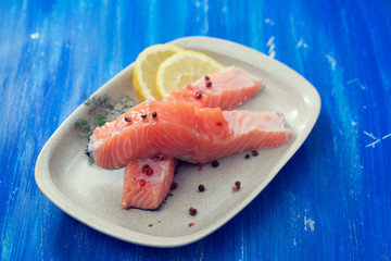 raw salmon with dill on white dish on blue wooden background