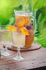 Glass of white sparkling wine sangria decorated with citrus slices and season fruits on wooden table.