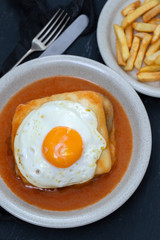 typical portuguese dish francesinha in dish on black ceramic background