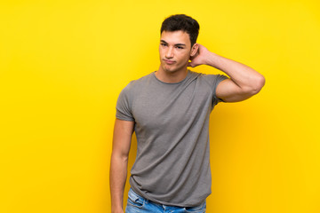 Handsome man over isolated yellow wall having doubts