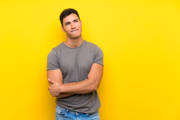 Handsome man over isolated yellow wall with confuse face expression - obrazy, fototapety, plakaty