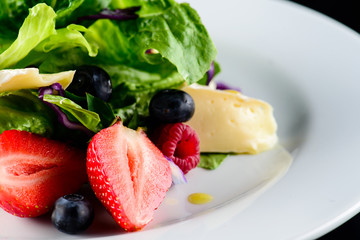 summer salad with avocado, strawberries and spinach, close up