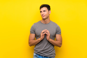 Handsome man over isolated yellow wall scheming something