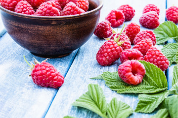 Fresh raspberry with leaves on a blue boards background. Selective focus.