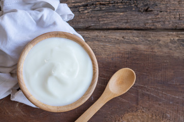 Fototapeta na wymiar Natural homemade plain organic yogurt in wooden bowl and wood spoon on wood texture background